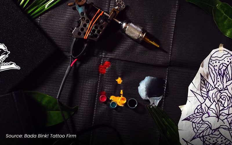 A tattoo gun and ink on a black surface