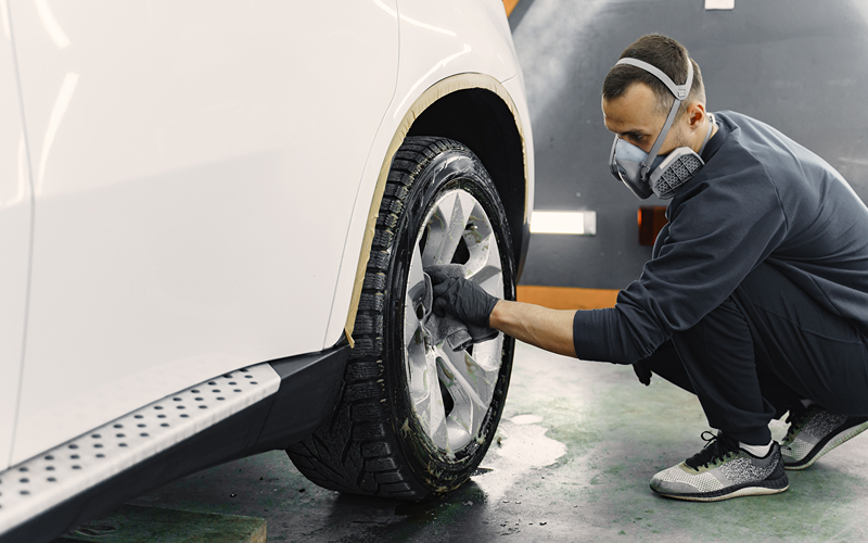 Image of a person cleaning car tyres