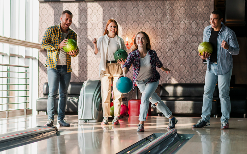 Image of a young adults playing bowling with drinks