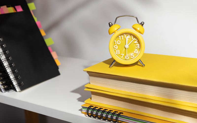 Image of an alarm clock on top of notebooks